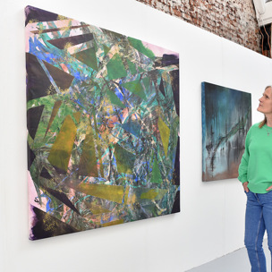woman admires artwork on wall in gallery - several works on display