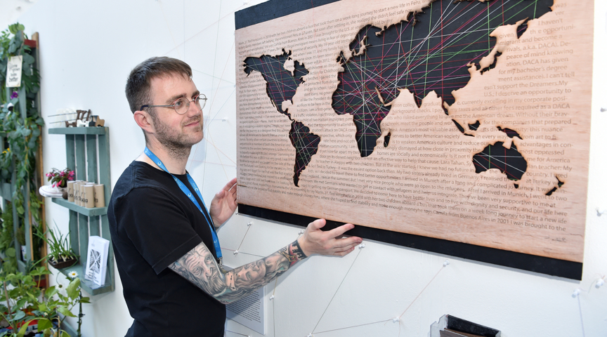 student looks at graphic world map artwork on wall of exhibition