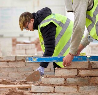 Two men laying bricks, one of them holding a spirit level.