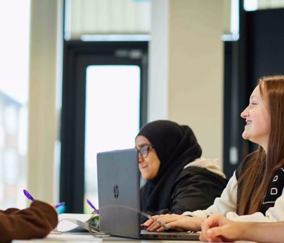 group of students working around table with laptop smiling