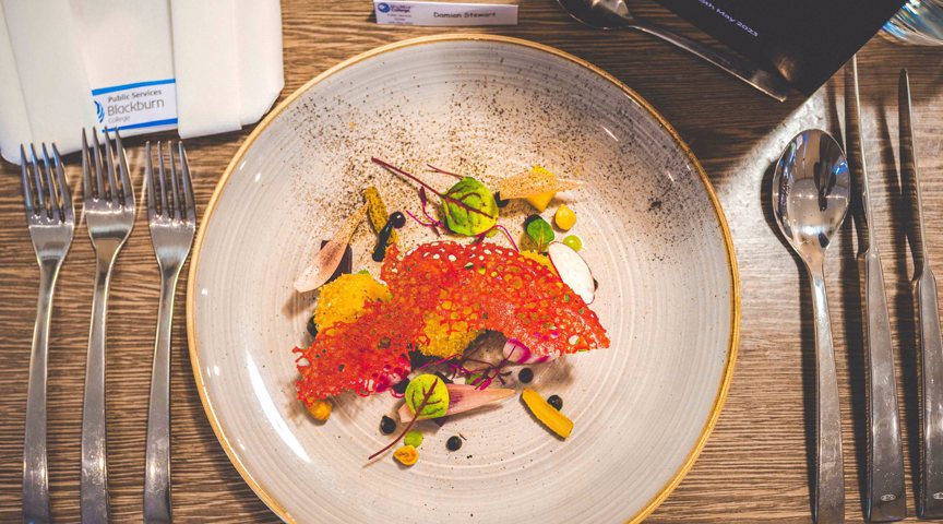 overhead shot of beautifully presented plate of food on table with cutlery