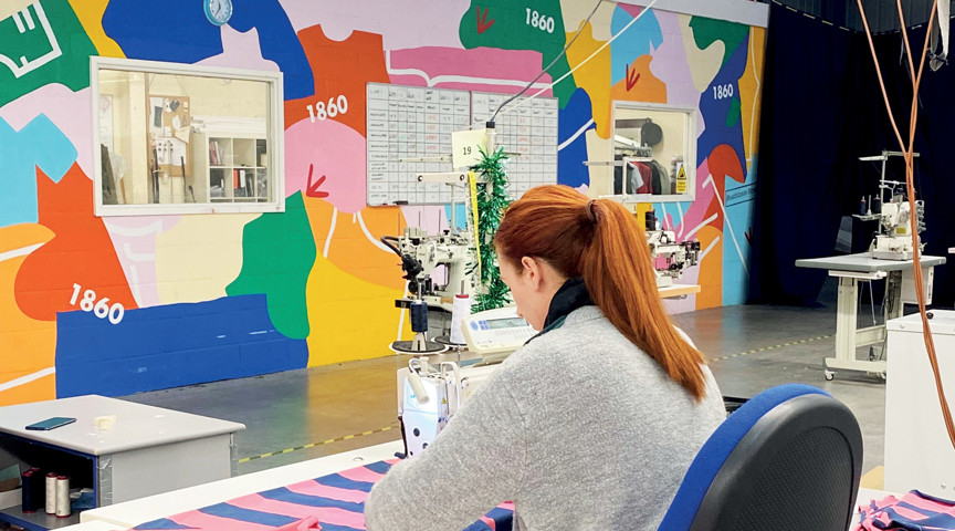 woman machine sewing material in room with brightly coloured walls