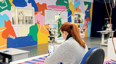 woman machine sewing material in room with brightly coloured walls