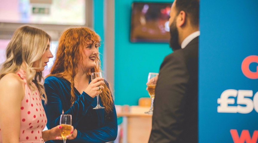 people smiling holding glasses of drinks in formal dinner wear