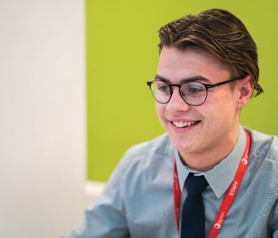 close up of young man smiling working at computer