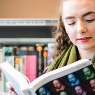 student reading shakespeare textbook in library