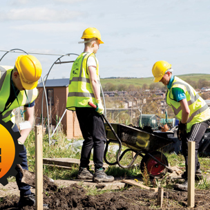 construction students digging soil and filling wheelbarrow