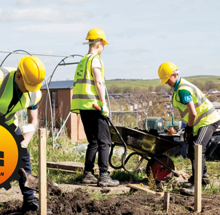 construction students digging soil and filling wheelbarrow