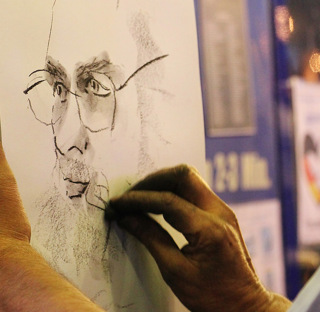 close up of person creating charcoal drawing of a face
