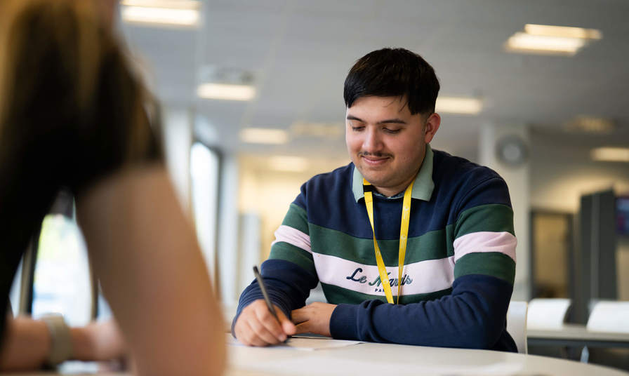 male student writing on paper