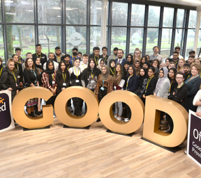 large group of people stood behind large gold letters spelling GOOD and Ofsted Good Provider signs