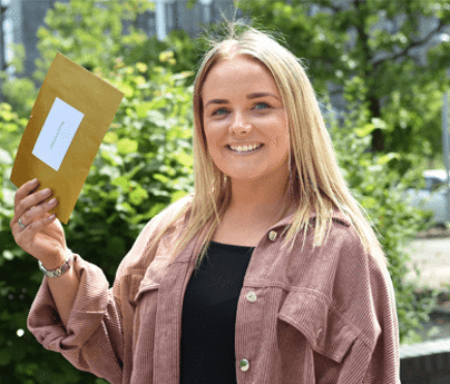 Rebecca Pilling smiles to camera holding golden envelope