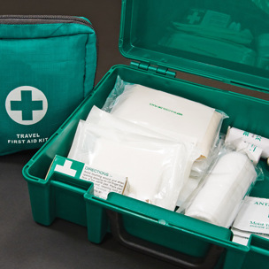 close up of open first aid box and travel kit with medical supplies