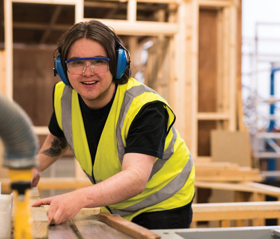 man wearing high-vis vest and safety goggles and glasses working on joinery machinery