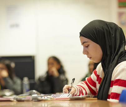 Closeup of student wearing headscarf working in classroom