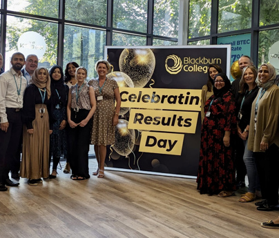 Members of staff standing in front of lightbox that says celebrating results day