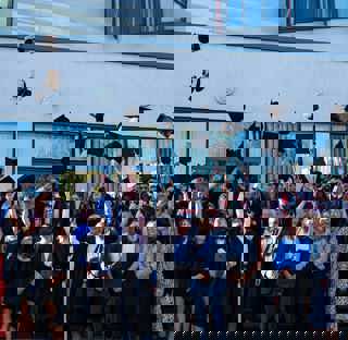 large group of graduates throwing hats into the air