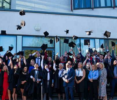 large group of graduates throwing hats into the air