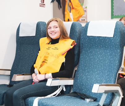 young women sat in aeroplane cabin seats wearing inflatable jackets