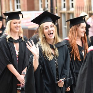 graduation procession close up of woman smiling and waving to camera