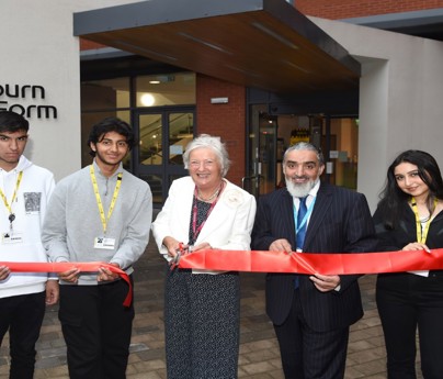 students alongside Lillian Croston and Dr Fazal Dad cut large red ribbon outside Blackburn Sixth Form