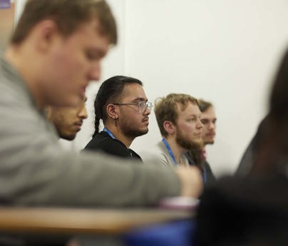 row of students sit in classroom listening