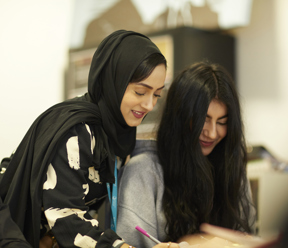Tutor leans over students to help with their work