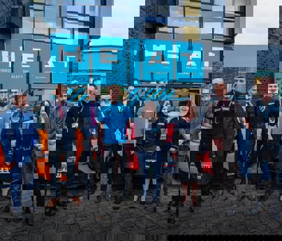 group of people stood in front of cards and HEAT Hybrid Electric Automotive Training building