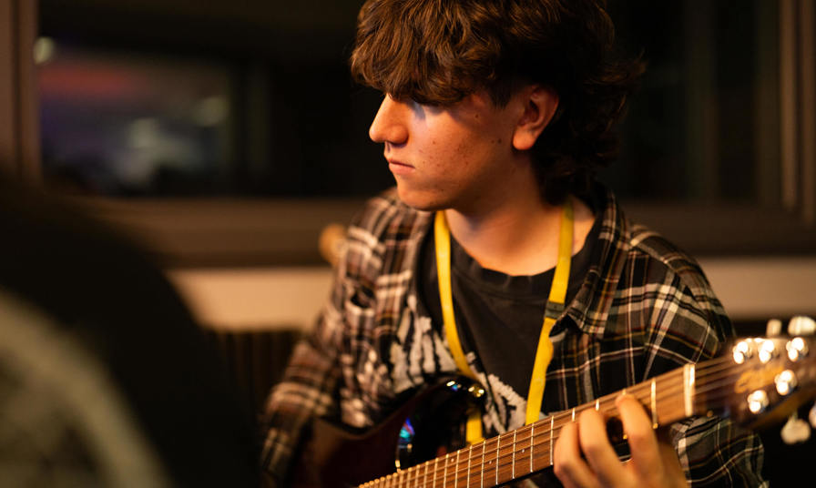 Young male student playing an electric guitar