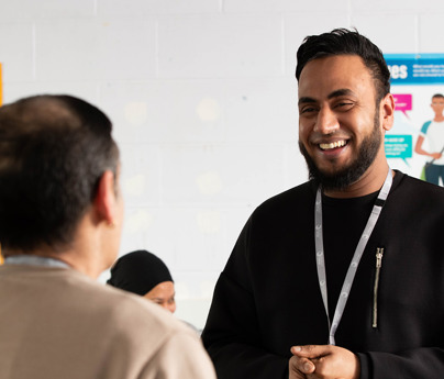 man stood smiling talking to other man in classroom