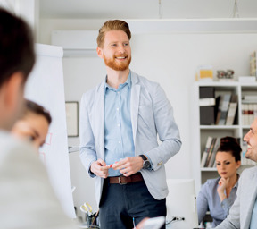 man stands in front of group smiling presenting with flipchart