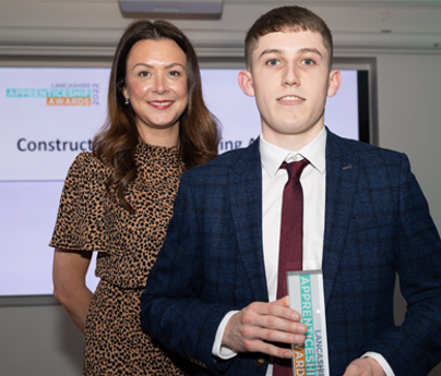 Matt Winstone holding Apprenticeship award with lady stood behind smiling