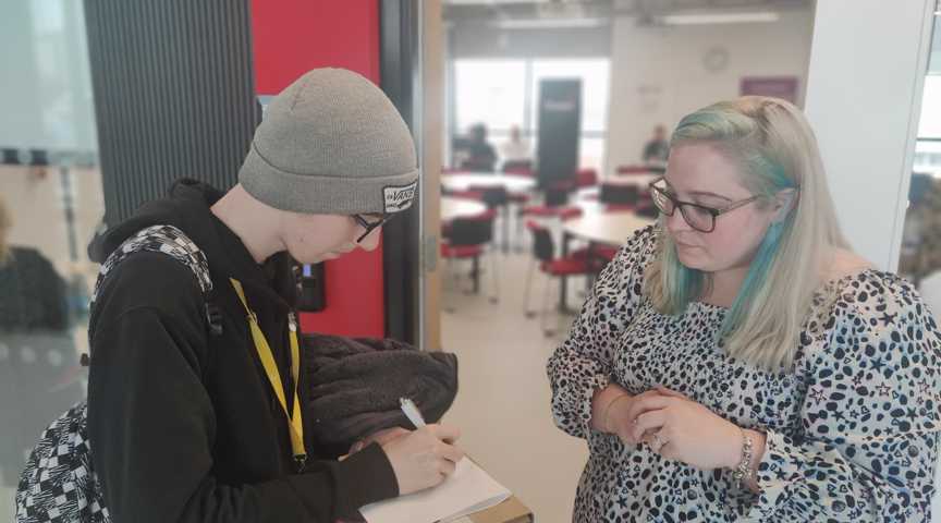 student makes notes whilst speaking to tutor