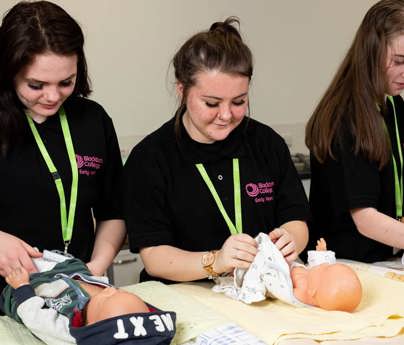 group of early years students changing dummy babies