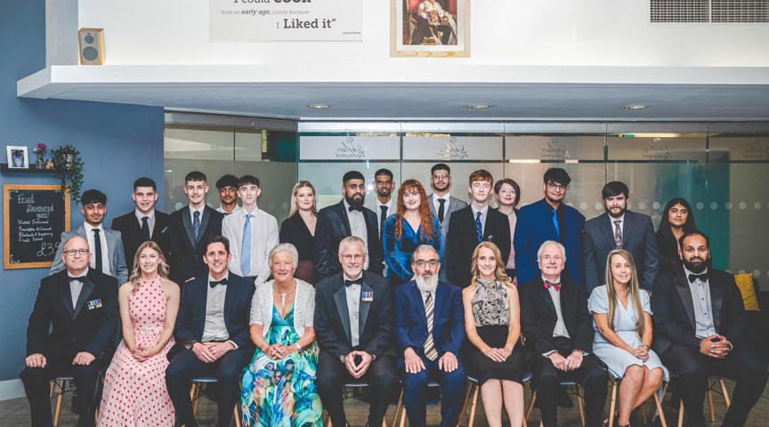 group of people in formal dinner wear in rows pose for photo