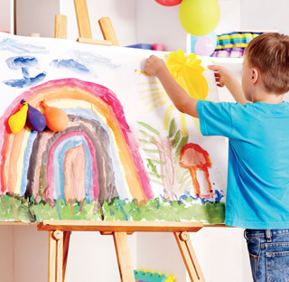 child with large paining of rainbow in garden on easel