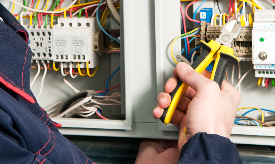 close up of person using snips on wiring in fuse box