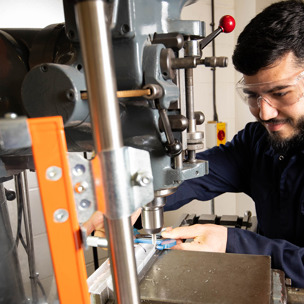 student in mechanics overalls working with engineering equipment