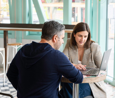 1 man and 1 woman talking looking at laptop on table