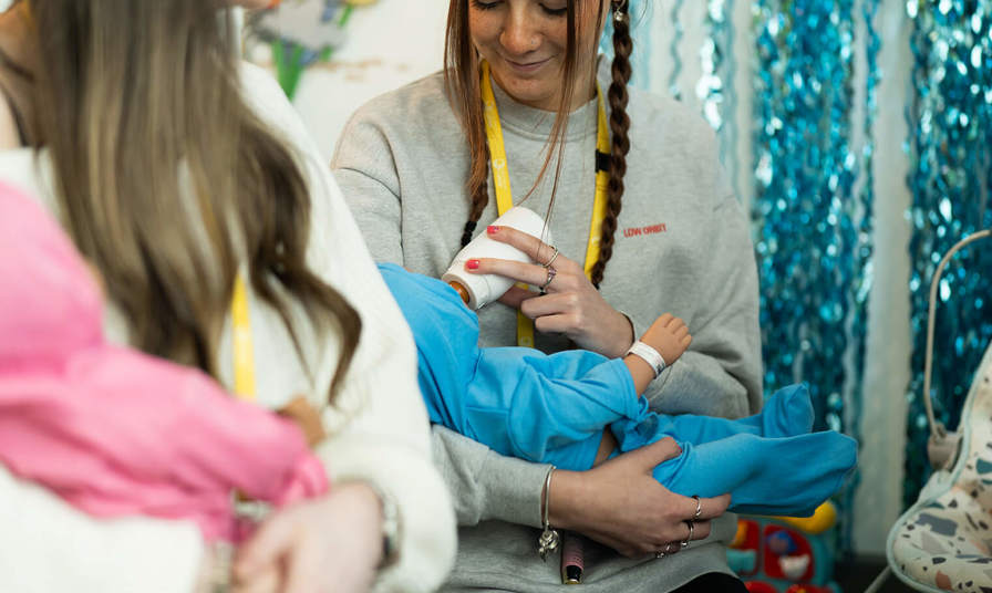 Young girl feeding practice baby doll with a bottle 