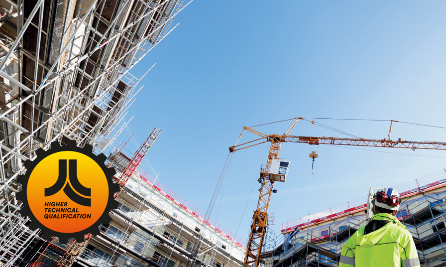 person in high-vis jacket and hard hat stands in construction site looking up at crane and scaffolding