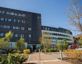 University Centre at Blackburn College building in the sunshine with trees and carpark