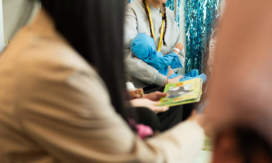 Young girl in the background holding a practice baby doll 
