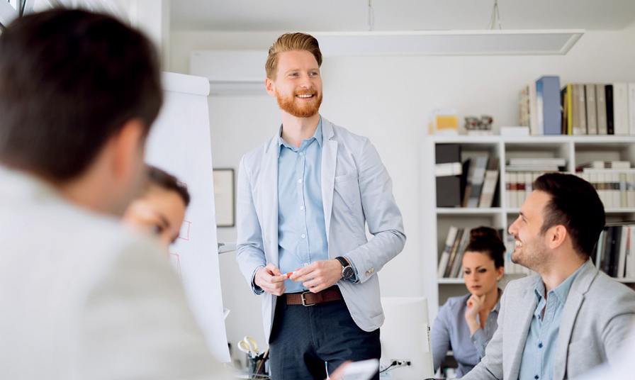 man stands in front of group smiling presenting with flipchart
