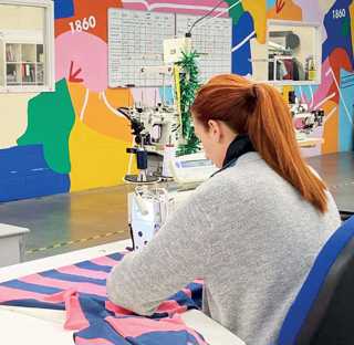 woman machine sewing material in room with brightly coloured walls