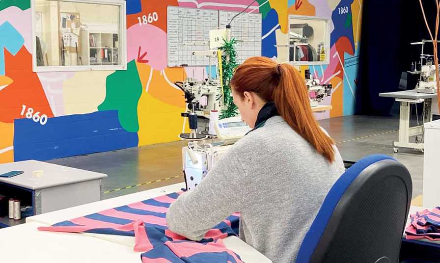 woman machine sewing material in room with brightly coloured walls