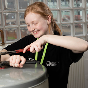 female plumbing student using tools on water system