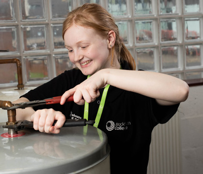 female plumbing student using tools on water system