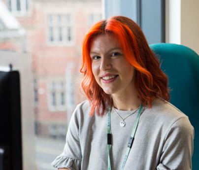 Smiling lady with red hair sat in office chair