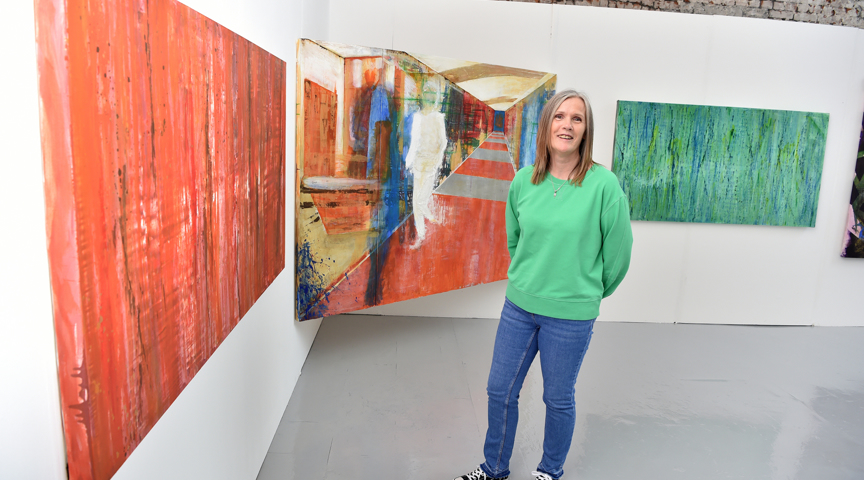 woman stood in art gallery in front of paintings with bright colours